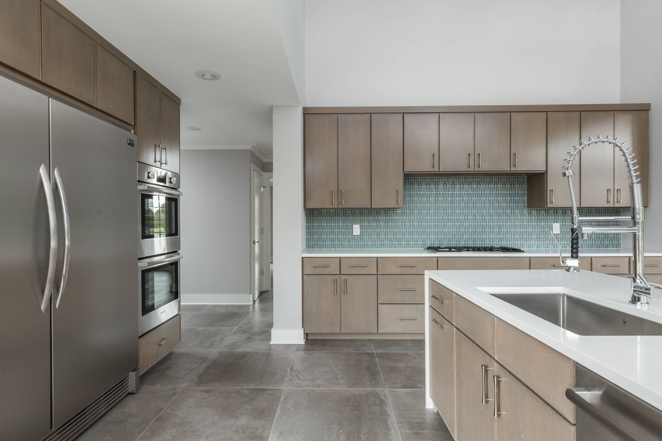 Spacious custom kitchen with stainless steel appliances, quartz countertops, and modern cabinetry by Eaton Custom Homes